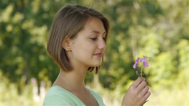 Jovem bela mulher cheirando flor — Vídeo de Stock