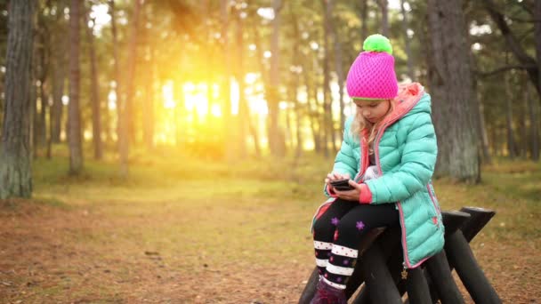 Vacker leende liten flicka med mobiltelefon — Stockvideo