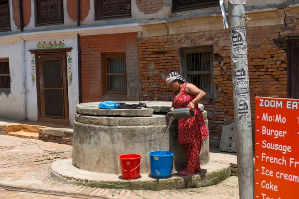 Женщина берет воду на маленькой улице — стоковое фото