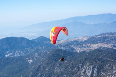 KEMER, TURKEY - 22 Ekim 2017: Türkiye 'nin Antalya ilindeki Türk Rivierası' nda bir sahil beldesi olan Kemer yakınlarındaki dağların üzerinden uçan paraglider