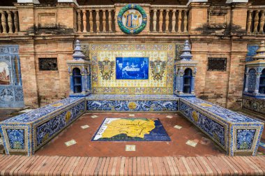 SEVILLE, SPAIN - 07 Nisan 2019: İspanya 'nın büyük bir turizm merkezi olan Seville' deki Plaza de Espana 'nın duvarları boyunca uzanan fayanslı taşra oyuğu