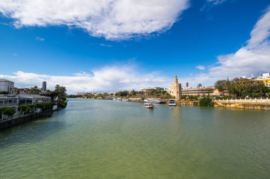 SEVILLE, SPAIN - 06 Nisan 2019: Guadalkivir nehri ve Torre del Oro, İspanya 'nın büyük bir turizm merkezi olan Seville' deki tarihi kireçtaşı kulesi