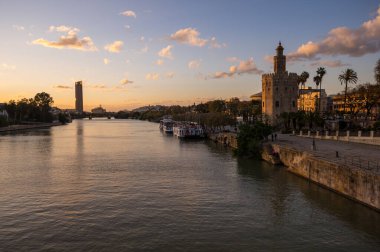SEVILLE, SPAIN - 06 Nisan 2019: Guadalkivir nehri ve Torre del Oro, İspanya 'nın büyük bir turizm merkezi olan Seville' deki tarihi kireçtaşı kulesi