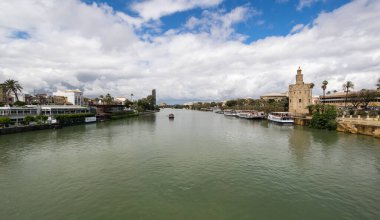 SEVILLE, SPAIN - 08 Nisan 2019: Guadalkivir nehri ve Torre del Oro, İspanya 'nın büyük bir turizm merkezi olan Seville' deki tarihi kireçtaşı kulesi