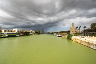 SEVILLE, SPAIN - 06 Nisan 2019: Guadalkivir nehri ve Torre del Oro, İspanya 'nın büyük bir turizm merkezi olan Seville' deki tarihi kireçtaşı kulesi