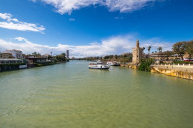SEVILLE, SPAIN - 06 Nisan 2019: Guadalkivir nehri ve Torre del Oro, İspanya 'nın büyük bir turizm merkezi olan Seville' deki tarihi kireçtaşı kulesi