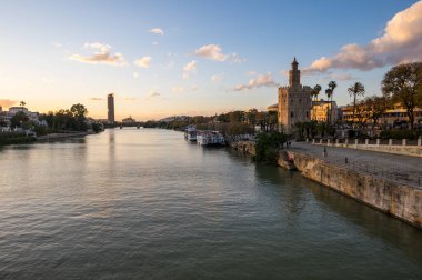 SEVILLE, SPAIN - 06 Nisan 2019: Guadalkivir nehri ve Torre del Oro, İspanya 'nın büyük bir turizm merkezi olan Seville' deki tarihi kireçtaşı kulesi