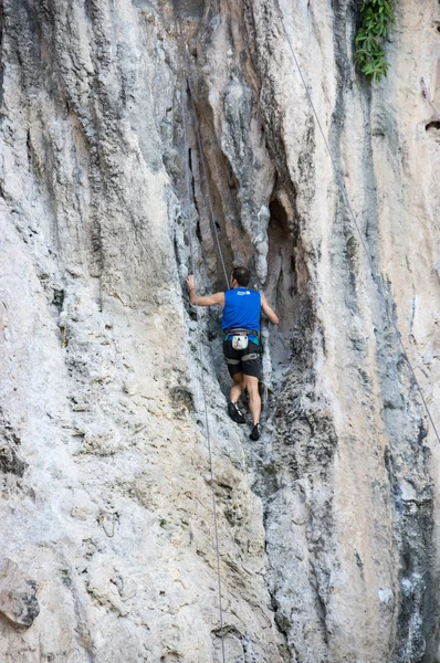 Un hombre trepando por un empinado acantilado de piedra caliza — Foto de Stock