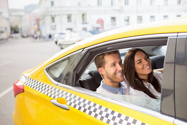 Casal sorridente em um táxi amarelo — Fotografia de Stock