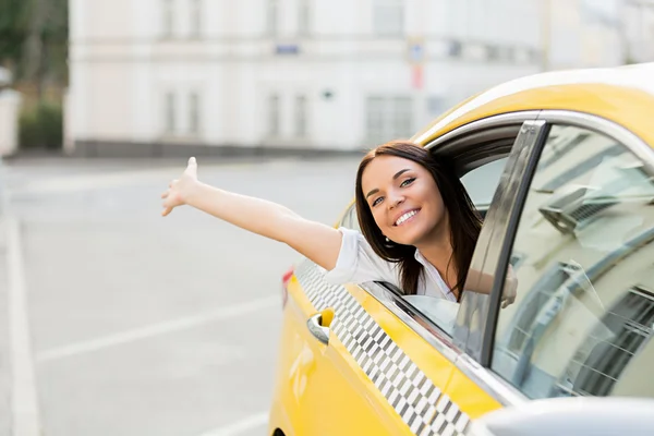 Aantrekkelijke vrouw in een gele taxi — Stockfoto