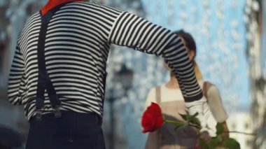 Pandomim şehirde genç bir kıza kırmızı bir gül veriyor.