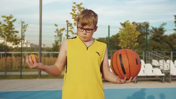 Νεαρό Αγόρι Που Ζυγίζει Μπάλα Και Πορτοκαλί Εξωτερικούς Χώρους — Αρχείο Βίντεο