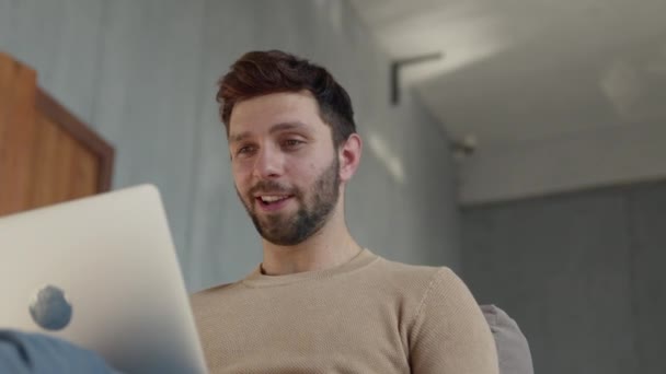 Joven hombre sonriente comunicándose por videoconferencia — Vídeos de Stock