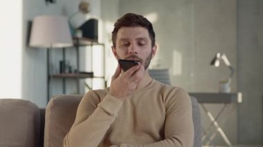 Genç adam evdeki telefondan bir sesli mesaj kaydediyor.