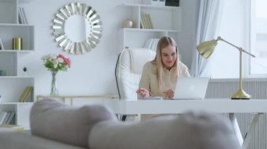 Gülümseyen genç kız masadaki bilgisayar, mikrofon ve web kamerasıyla canlı olarak iletişim kuruyor.