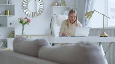 Smiling young woman communicating by video live using computer, microphone and webcam