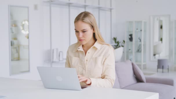 Attractive girl at the desk with a laptop in a white room. Portrait of young woman with laptop — Stock Video