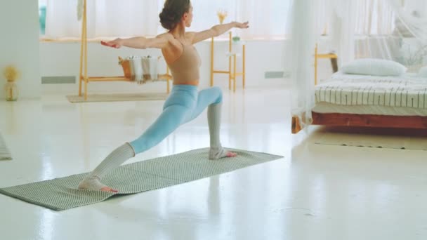 Jovem yogist em sportswear fazendo ioga em casa. Mulher atraente fazendo exercício na sala — Vídeo de Stock