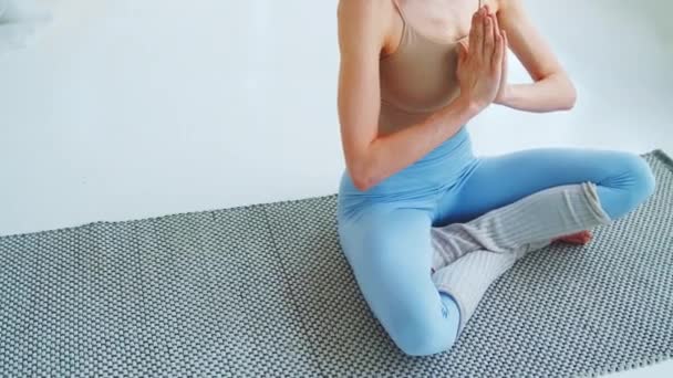 Junges Mädchen in Yoga-Lotusposition im Wohnzimmer. Attraktive Frau meditiert mit ihren Händen — Stockvideo