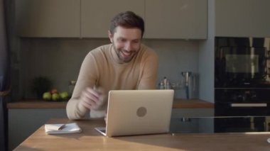 Gülümseyen adam kameraya bakıyor. Evde konuşuyor. Genç adam randevulaşma videosu çekiyor.