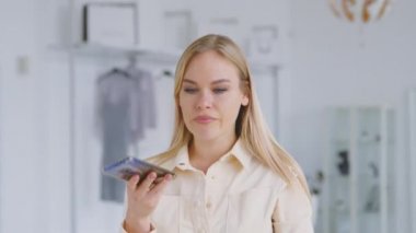 Ciddi duygusal bir kadın akıllı telefondan kapalı alanda sesli mesajlar kaydediyor. Çekici kız sesli mesaj kaydediyor.