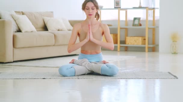 Belle femme assise en position lotus avec les mains en namaste. Jeune femme faisant du yoga les yeux fermés — Video