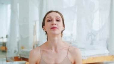 Genç yoga eğitmeni kameraya bakıyor. Atletik kız ders veriyor.