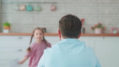 Şirin küçük kız evde tatil için babasına kart veriyor. Babalar Günü tatilinde mutlu aile.