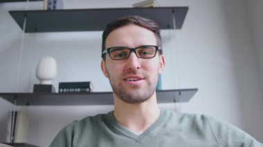 Ofisteki video bağlantısıyla dizüstü bilgisayara bakan gülümseyen adam. Genç bir erkek kamerayla konuşuyor, yavaş çekim.