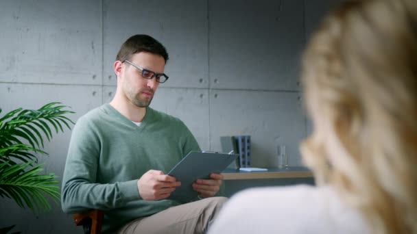 Jovem psicoterapeuta conversando com um paciente em um sofá — Vídeo de Stock