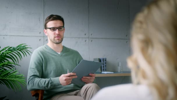 Joven profesional hablando con un paciente en un consultorio — Vídeos de Stock