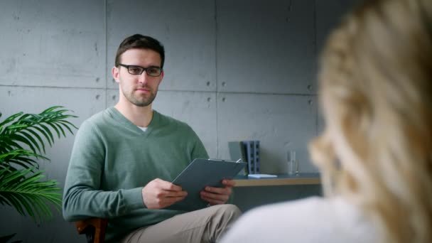 Ung lyssnande psykolog med en patient på kontoret. Ung flicka vid receptionen — Stockvideo