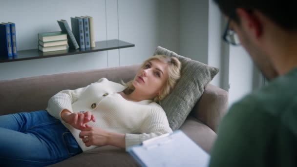 Μια νεαρή γυναίκα στον καναπέ λέει στον ψυχολόγο για τα προβλήματα. Επαγγελματίας διεξάγει ψυχολογική θεραπεία σε μια νεαρή γυναίκα — Αρχείο Βίντεο