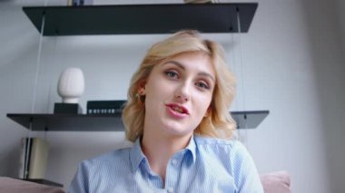 Ofisteki video bağlantısıyla konuşan gülümseyen öğretmen. Genç gülümseyen kadın kamerayla konuşuyor, yavaş çekim.