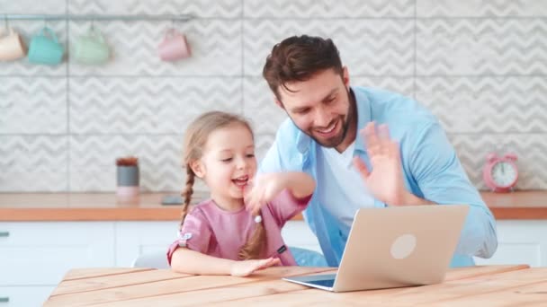 Młoda rodzina z dzieckiem rozmawiająca przez mikrofon i kamerę internetową. Uśmiechnięty tata i mała córeczka rozmawiają z mamą na konferencji online — Wideo stockowe