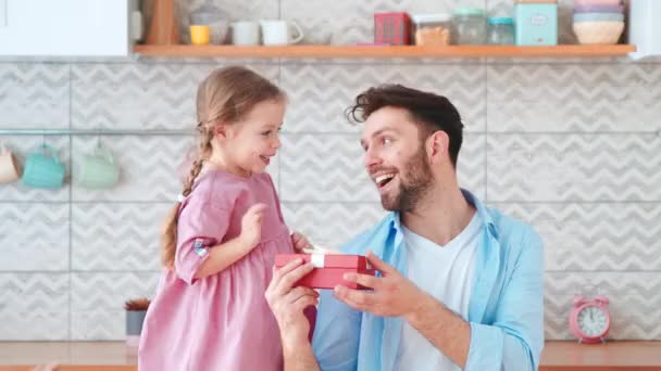 Joyeux fille reçoit un cadeau d'anniversaire de papa. Jeune père donnant un cadeau à sa petite fille à la maison — Video