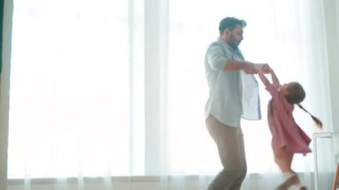 Genç bir baba, küçük kızını evin içinde daireler çiziyor. Babalar Günün kutlu olsun.