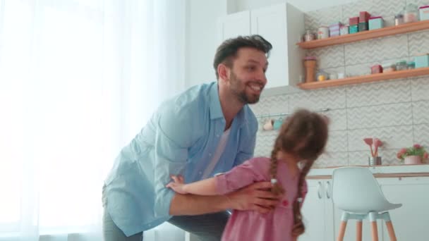 Padre sorridente che gira intorno alla figlioletta all'interno della casa. Famiglia felice — Video Stock