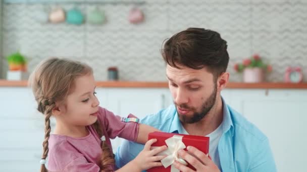 Cute little girl giving a gift to dad for a holiday in the living room. One parent with a child at home — Stock Video