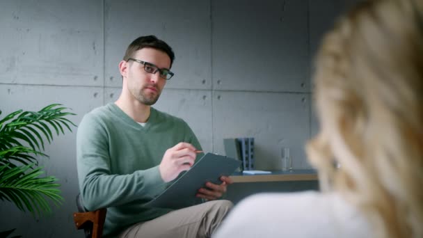 Ung psykoterapeut med en patient på kontoret. Psykoterapeuten som förklarar planen för patienten — Stockvideo