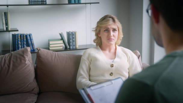 Jonge vrouwelijke patiënt in gesprek met de dokter tijdens de psychologische sessie op kantoor. Aantrekkelijke vrouw op de bank praten over haar problemen — Stockvideo
