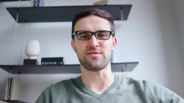 Genç adam ofisteki video bağlantısıyla dizüstü bilgisayara bakıyor. Genç bir erkek kamerayla konuşuyor, yavaş çekim.