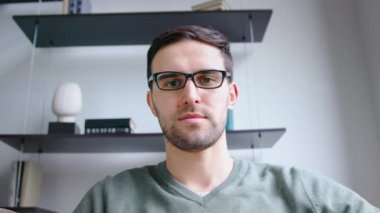 Ofisteki video bağlantısıyla dinleyen genç adam. Genç erkek web kamerası görüntülerine bakıyor, yavaş çekim.