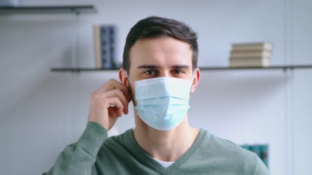 Hombre joven quitándose la máscara médica y sonriendo mientras mira a la cámara. Concepto de estilo de vida — Vídeo de stock