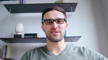 Ofisteki video bağlantısıyla dizüstü bilgisayara bakan gülümseyen adam. Genç bir erkek kamerayla konuşuyor, yavaş çekim.