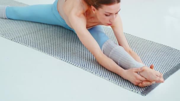 Chica joven estirándose en la alfombra en casa. Mujer relajante haciendo yoga en casa — Vídeos de Stock