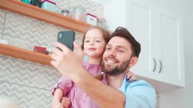 Genç baba ve küçük kız akıllı telefondan selfie çekiyorlar. Baba ve kızı birlikte vakit geçiriyorlar.