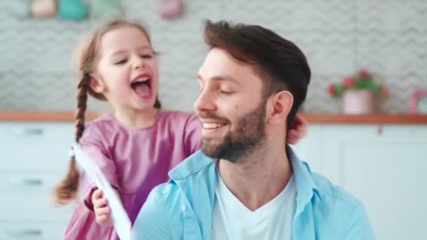 Schattig klein meisje geeft een kaart aan papa voor een vakantie in de woonkamer — Stockvideo