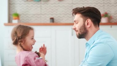 Evdeki mutfakta baba ve küçük kız konuşuyor. Aile hafta sonu