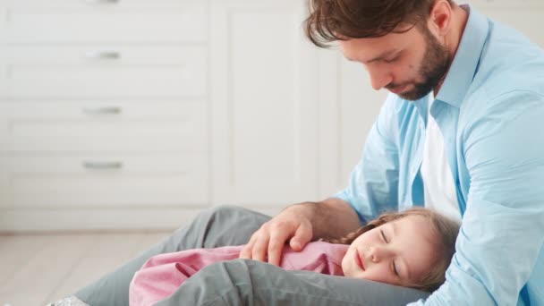 Sleeping little daughter in her fathers arms at home. Tender love of father and daughter — Stock Video